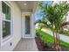 Inviting front entrance features a glass door, decorative palm tree and lush landscaping at 9031 Duany Ln, Lakewood Ranch, FL 34240