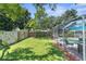 Spacious backyard with fenced yard, grassy area, and screened pool at 6156 Montana Ave, New Port Richey, FL 34653