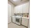 Bright laundry room with white cabinets and modern washer/dryer at 5013 Sevilla Shores Dr, Wimauma, FL 33598