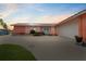 Pink mid-century modern home with attached garage, mature landscaping, and spacious driveway at 351 Harbor Psge, Clearwater Beach, FL 33767