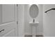Stylish powder room featuring a pedestal sink with a modern faucet, an oval mirror, and a sleek towel bar at 9019 Rothman Ln, Lakewood Ranch, FL 34240