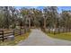 Long driveway leading up to the gated home with fencing and mature trees at 15734 Old Mill Pond Rd, Dade City, FL 33523