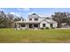 Stunning two-story farmhouse with metal roof, dark wood shutters and charming front porch at 15734 Old Mill Pond Rd, Dade City, FL 33523