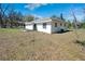 Exterior backyard view features a white house with a covered patio and a spacious lawn at 33021 Ranch Rd, Dade City, FL 33523