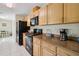 Well-lit kitchen featuring wood cabinetry, black appliances, granite countertops, and white tile flooring at 33021 Ranch Rd, Dade City, FL 33523