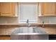Close-up of the stainless steel farm sink with granite countertops and wooden cabinets, under a window at 33021 Ranch Rd, Dade City, FL 33523