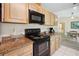 Close-up of the kitchen featuring wood cabinetry, black appliances, granite countertops, and white tile flooring at 33021 Ranch Rd, Dade City, FL 33523