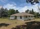 Back exterior of home, including covered porch and back yard with trees at 33021 Ranch Rd, Dade City, FL 33523