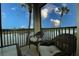 Relaxing balcony with wicker furniture overlooking a serene lake and palm trees at 7005 River Hammock Dr # 207, Bradenton, FL 34212