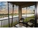 Relaxing balcony with wicker furniture overlooking a serene lake and palm trees at 7005 River Hammock Dr # 207, Bradenton, FL 34212