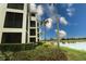 Exterior of a multi-story condo building with lush landscaping and a scenic lake view at 7005 River Hammock Dr # 207, Bradenton, FL 34212