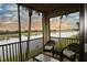 Relaxing screened patio with wicker furniture overlooking a lake and lush greenery at 7005 River Hammock Dr # 207, Bradenton, FL 34212