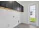 Modern laundry room with black cabinets, white walls, and a door to the outside at 9015 Rothman Ln, Lakewood Ranch, FL 34240