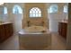 An exquisite bathroom featuring a tiled tub, dual vanities, and arched windows for natural light at 13550 Thoroughbred Dr, Dade City, FL 33525