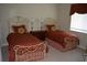 A cozy guest bedroom features twin beds with decorative wrought iron headboards, pillows and window treatments at 13550 Thoroughbred Dr, Dade City, FL 33525