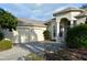 Stately home featuring a three-car garage, arched entryway, and beautifully landscaped front yard at 13550 Thoroughbred Dr, Dade City, FL 33525