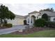 Elegant home exterior featuring a three car garage, arched entryway, and professionally landscaped front yard at 13550 Thoroughbred Dr, Dade City, FL 33525