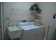 Well-equipped laundry room features a sink, washer, dryer, shelving, and decorative plant for a touch of nature at 13550 Thoroughbred Dr, Dade City, FL 33525