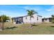 Well-maintained backyard with lush green grass, mature palm tree, and screened-in porch at 8461 Buttonquail Dr, Englewood, FL 34224