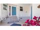 Charming entrance with blue door, stairs with white railing, and colorful floral accents at 8461 Buttonquail Dr, Englewood, FL 34224