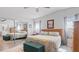 Bright bedroom features a mirrored closet, neutral walls, and a cushioned bench at the foot of the bed at 8461 Buttonquail Dr, Englewood, FL 34224