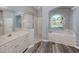 Bright bathroom featuring a soaking tub, glass shower, dual vanity, and modern gray wood-look flooring at 519 Purslane Pt, Venice, FL 34293