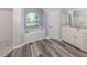 Bright bathroom featuring a soaking tub, glass shower, dual vanity, and modern gray wood-look flooring at 519 Purslane Pt, Venice, FL 34293