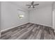 Bright bedroom with ceiling fan, large window and modern gray wood-look flooring at 519 Purslane Pt, Venice, FL 34293