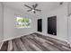 Bright bedroom with ceiling fan, large window and modern gray wood-look flooring at 519 Purslane Pt, Venice, FL 34293