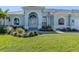Inviting home featuring arched windows, a bright green lawn, and lush landscaping enhances its curb appeal at 519 Purslane Pt, Venice, FL 34293