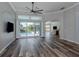 Spacious living room with wood-look floors, large windows, and sliding glass doors to the pool area at 519 Purslane Pt, Venice, FL 34293