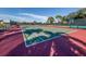 Outdoor tennis court with red and green surfaces surrounded by lush greenery for the avid player at 519 Purslane Pt, Venice, FL 34293