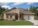 Charming single-story home featuring a two-car garage, well-manicured lawn, and neutral-toned stucco exterior at 17350 Crisp Apple Ln, Land O Lakes, FL 34638