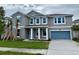 Gray two-story home with a one-car garage, palm trees, blue shutters, and white trim at 9572 Brave Buck Ave, Land O Lakes, FL 34638