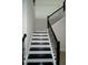 Staircase with black steps, white risers, a black railing and tiled floors at 9572 Brave Buck Ave, Land O Lakes, FL 34638