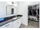 Bathroom vanity with white cabinets, black countertop and a mirror, adjoins a walk-in closet for convenience at 3708 Alafia Creek St, Plant City, FL 33567