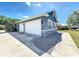 Three-car garage featuring stone accents, exterior lighting, and a paved driveway under a sunny blue sky at 3708 Alafia Creek St, Plant City, FL 33567