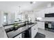 Bright kitchen featuring white cabinets, a spacious black countertop island, and stylish pendant lighting at 3708 Alafia Creek St, Plant City, FL 33567