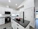 Well-lit kitchen with white cabinetry, black countertops, a central island, and contemporary appliances at 3708 Alafia Creek St, Plant City, FL 33567