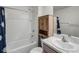 Clean bathroom with a shower, tub, sink, and a wood cabinet over the toilet at 38370 Sonnet Landing Ave, Zephyrhills, FL 33540