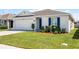 Attractive single-story home showcasing vibrant landscaping, a two-car garage, and a beautiful blue front door at 38370 Sonnet Landing Ave, Zephyrhills, FL 33540