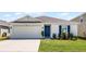 Charming single-story home featuring a well-maintained lawn, a two-car garage, and a vibrant blue front door at 38370 Sonnet Landing Ave, Zephyrhills, FL 33540