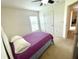 This bedroom features a cozy bed with a purple comforter, a ceiling fan and a window at 6698 Wirevine Dr, Brooksville, FL 34602