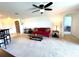 A well lit living room featuring a red sofa, carpet flooring and ceiling fan at 6698 Wirevine Dr, Brooksville, FL 34602