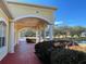 Spacious covered patio featuring brick flooring, white pillars, and views of the community lake and landscaping at 6698 Wirevine Dr, Brooksville, FL 34602