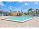 Community pool area surrounded by brick pavers, palm trees, and various seating arrangements at 12300 Vonn Rd # 1102, Largo, FL 33774