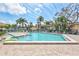 Community pool with blue lounge chairs, palm trees, and a paved patio, perfect for relaxation and recreation at 12300 Vonn Rd # 1102, Largo, FL 33774