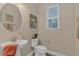 Powder room with pedestal sink, toilet, and framed artwork; window provides natural light at 7575 Sea Oak Ct, Parrish, FL 34219