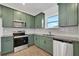 Stainless steel appliances and stylish olive green cabinets complete the kitchen at 9608 Brave Buck Ave, Land O Lakes, FL 34638