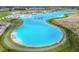 An aerial view of a community lagoon with a white sand beach and inflatable waterpark at 11728 June Briar Loop, San Antonio, FL 33576